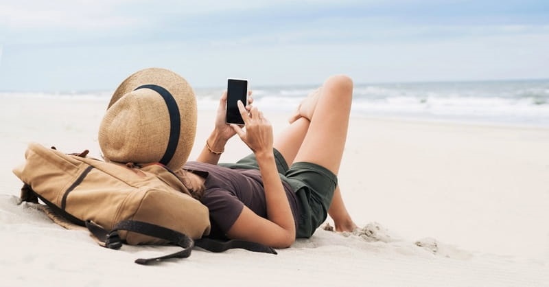 Woman using cell phone on the beach