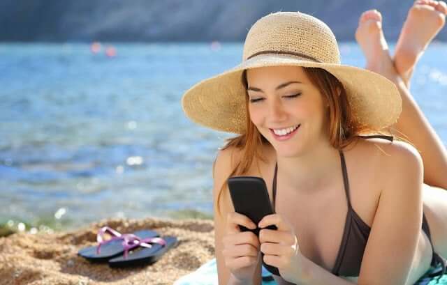 Girl using cell phone on the beach